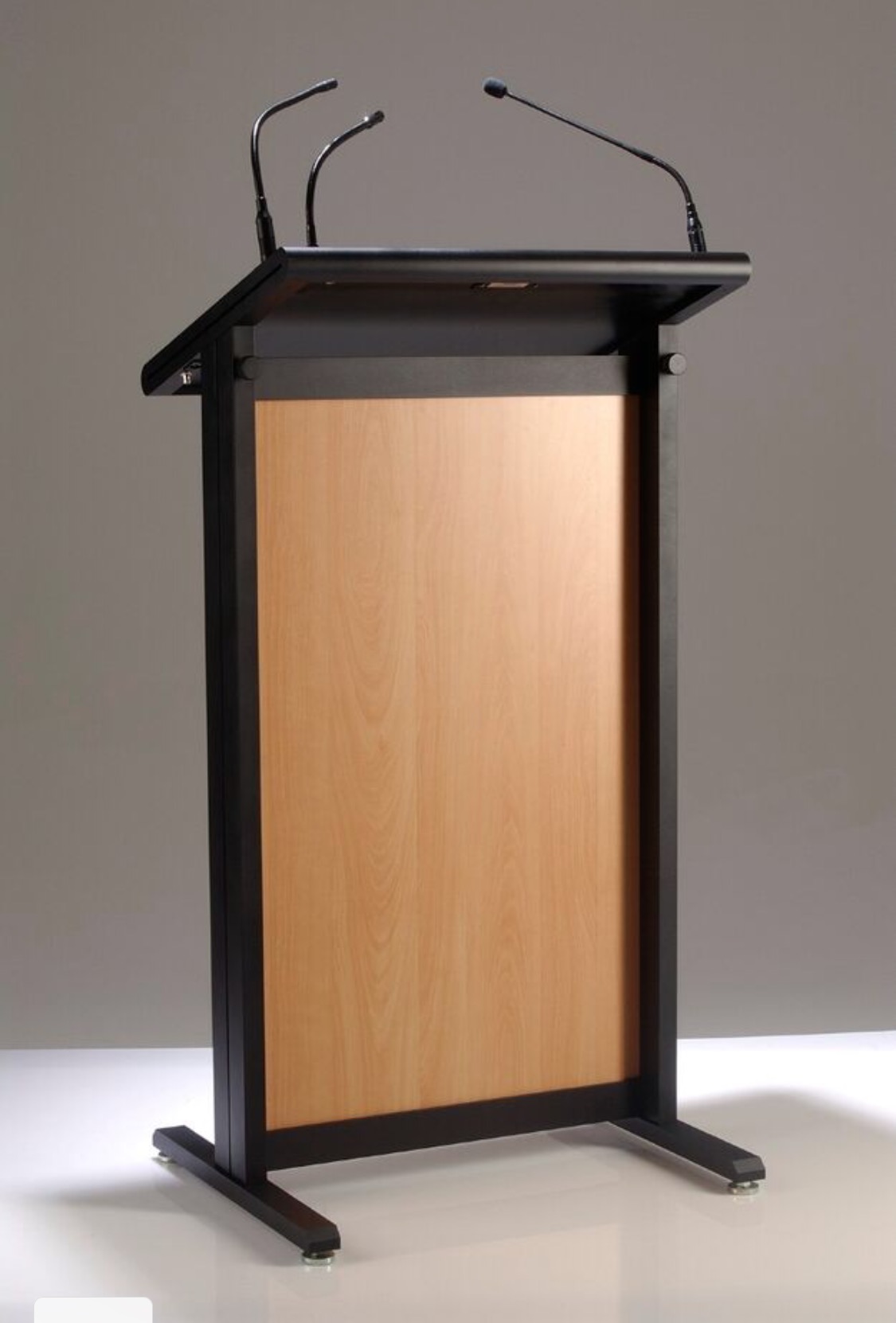 Professional black floor-standing lectern with a warm wood front panel and integrated dual microphone and light sockets.